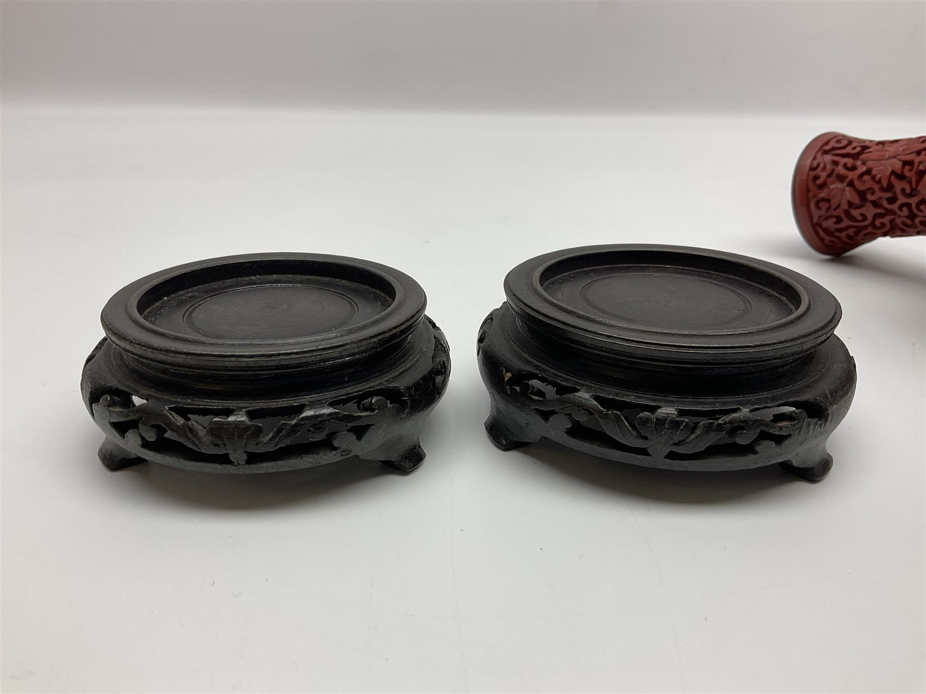 Pair of Chinese cinnabar lacquer vases, each of bulbous baluster form, carved with peonies and foo dogs amongst scrolls, with blue enamel interior and upon wooden bases, H20cm