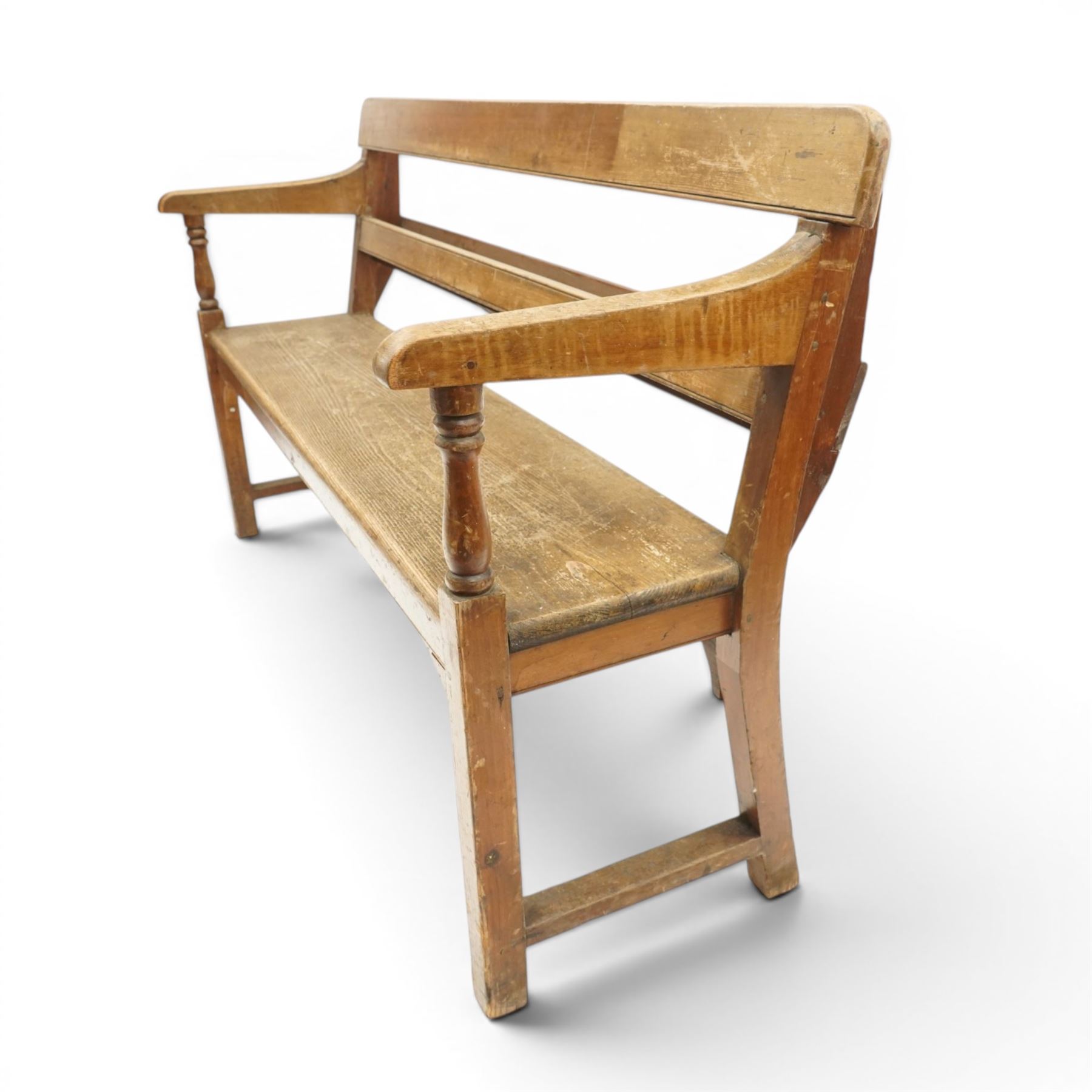 Early 20th century pine chapel bench, with moulded plank back rail over plain rail, with book storage to the back, open shaped end supports with curved arms, turned front uprights, plank seats, square legs united by low stretchers