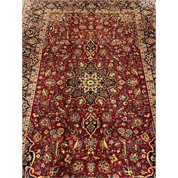 Persian red ground Kashan rug, all over floral design with interlaced foliate and stylised flower heads, repeating scrolled border with plant motifs