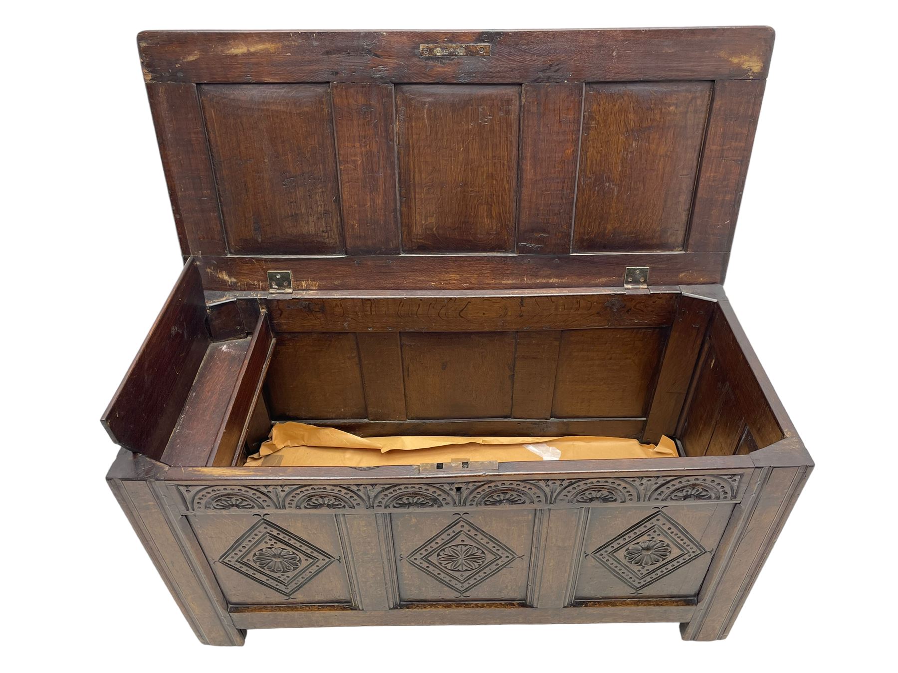 18th century oak coffer or chest, rectangular triple panelled hinged top with moulded edge enclosing main compartment and candle box, the frieze carved with repeating concentric lunettes and foliate patterns, the front fielded panels decorated with lozenges containing central flower heads, on stile supports