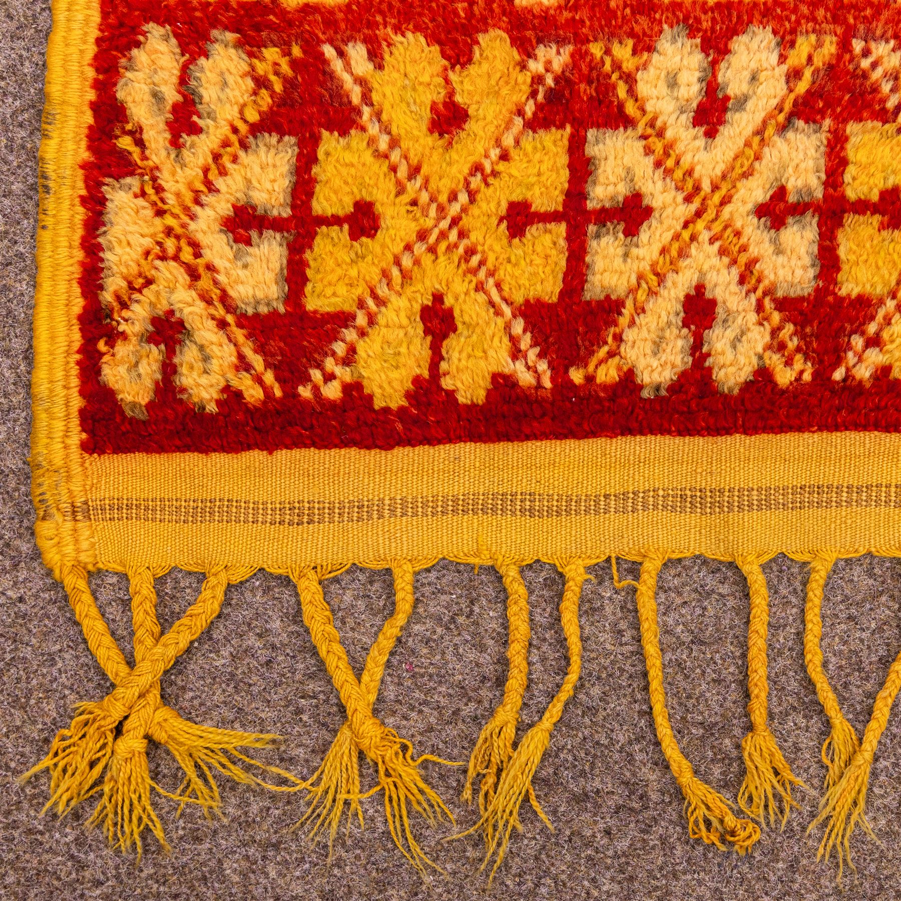 Moroccan Berber hand knotted runner, the red and orange ground woven with an all over lattice of lozenge motifs enclosing small geometric devices, within narrow patterned borders, finished with fringe to one end