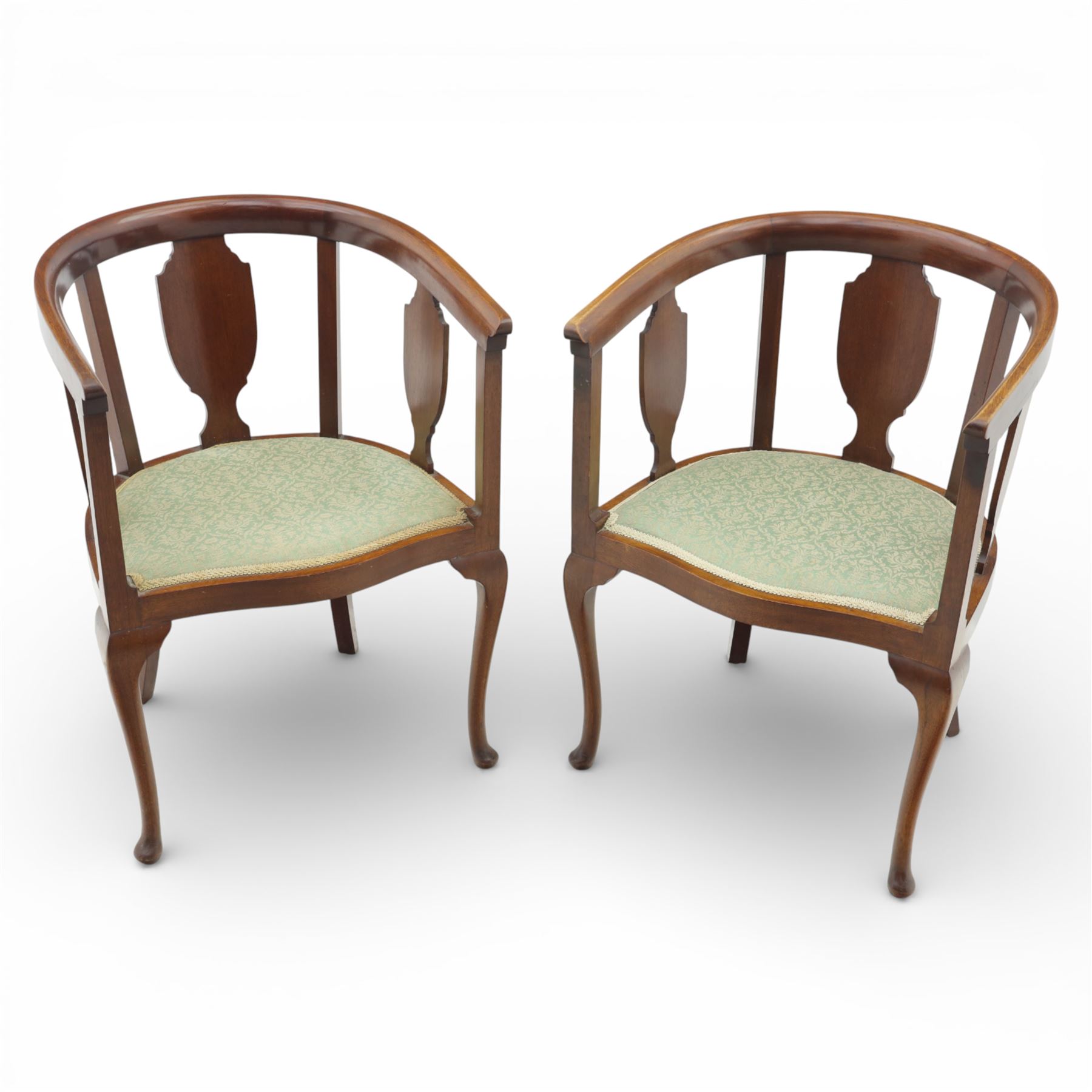 20th century mahogany tub chairs, the arched backs enclosing shaped splat panels and plain uprights, open curved arms flowing into the seat rails, upholstered seats in green foliate patterned fabric, on cabriole legs