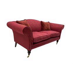 Traditional design two seat sofa, upholstered in red fabric, turned mahogany feet with brass castors