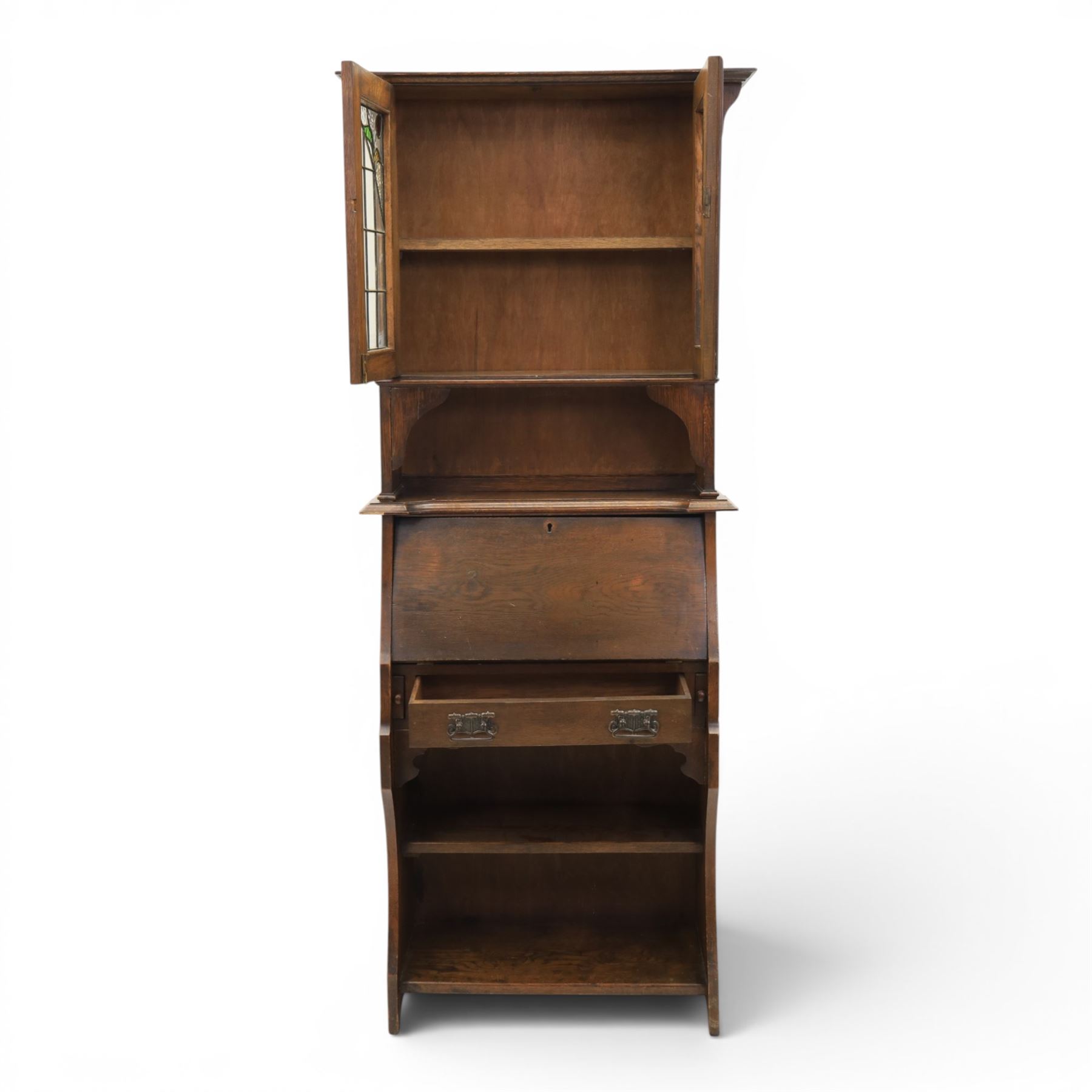 Arts & Crafts oak bureau bookcase, projecting cornice with leaded and glazed upper cabinet, the lower section with fall front section revealing a fitted interior, above shaped lower shelving 