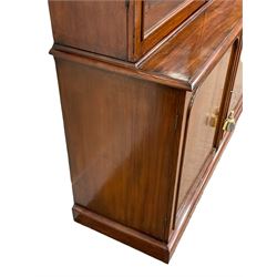 Victorian mahogany library bookcase on cupboard, projecting moulded cornice over two glazed doors in arched frames with moulded slips, fitted with four adjustable shelves, the cupboard with moulded rectangular top over two panelled arched doors, moulded plinth base