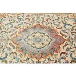 Fine Persian silk inlaid ivory and rose ground Tabriz rug, the busy field decorated with a central foliate pole medallion surrounded by scrolling foliage with trailing flowerheads and bouquets, the multiple guard lines filled with repeating scrolling palmettes and interlocking floral motifs