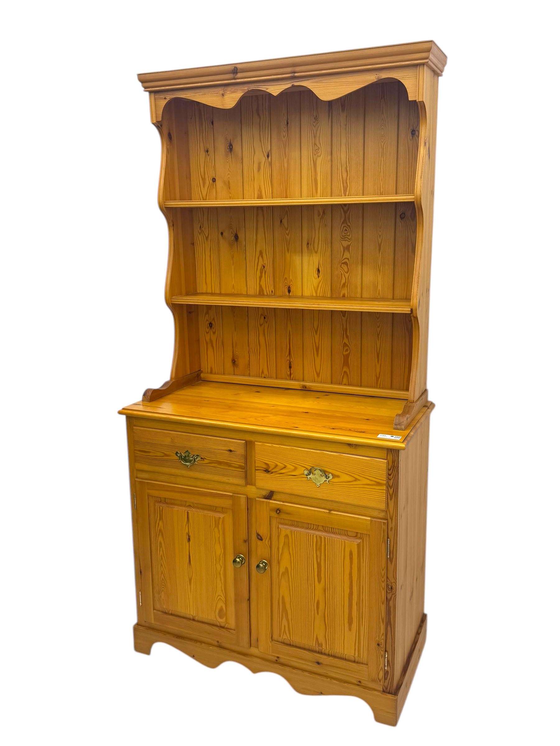 Victorian design pine dresser, projecting moulded cornice over scalloped frieze and two open shelves, base fitted with two drawers over double cupboard, on shaped plinth base