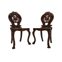 Pair late 19th century mahogany hall chairs, carved and pierced back with central shield surrounded by scrolling, serpentine shaped seat raised on scrolled cabriole supports