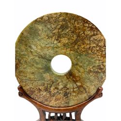 Large Chinese green and russet jade Bi-Disc, engraved with Taotie masks and tigers in the style of the Western Han dynasty, upon carved hardwood stand, disk D21cm