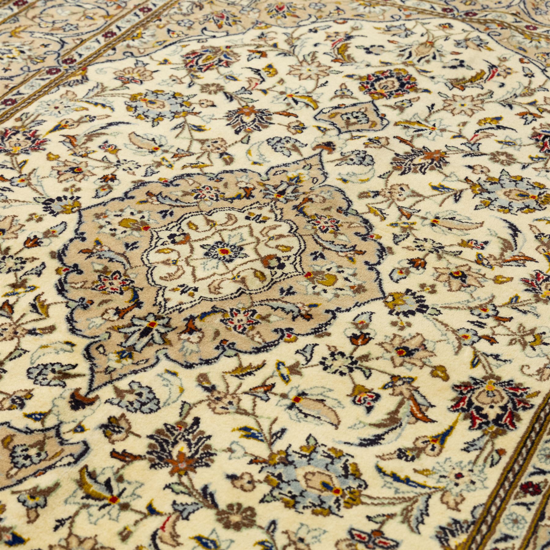 Central Persian Kashan hand-knotted rug, ivory ground, with a central shaped floral medallion with pendants, surrounded by scrolling foliate and floral motifs incorporating rosettes, palmettes and delicate vine work, enclosed by a beige border with repeating palmettes and meandering vines, flanked by narrow floral guard stripes, with cotton fringes