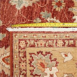 Persian Chubi Oushak style revival hand-knotted carpet, madder red field decorated with large-scale stylized palmettes and floral sprays framed by a broad pale golden border with simplified foliate motifs and multiple guard stripes