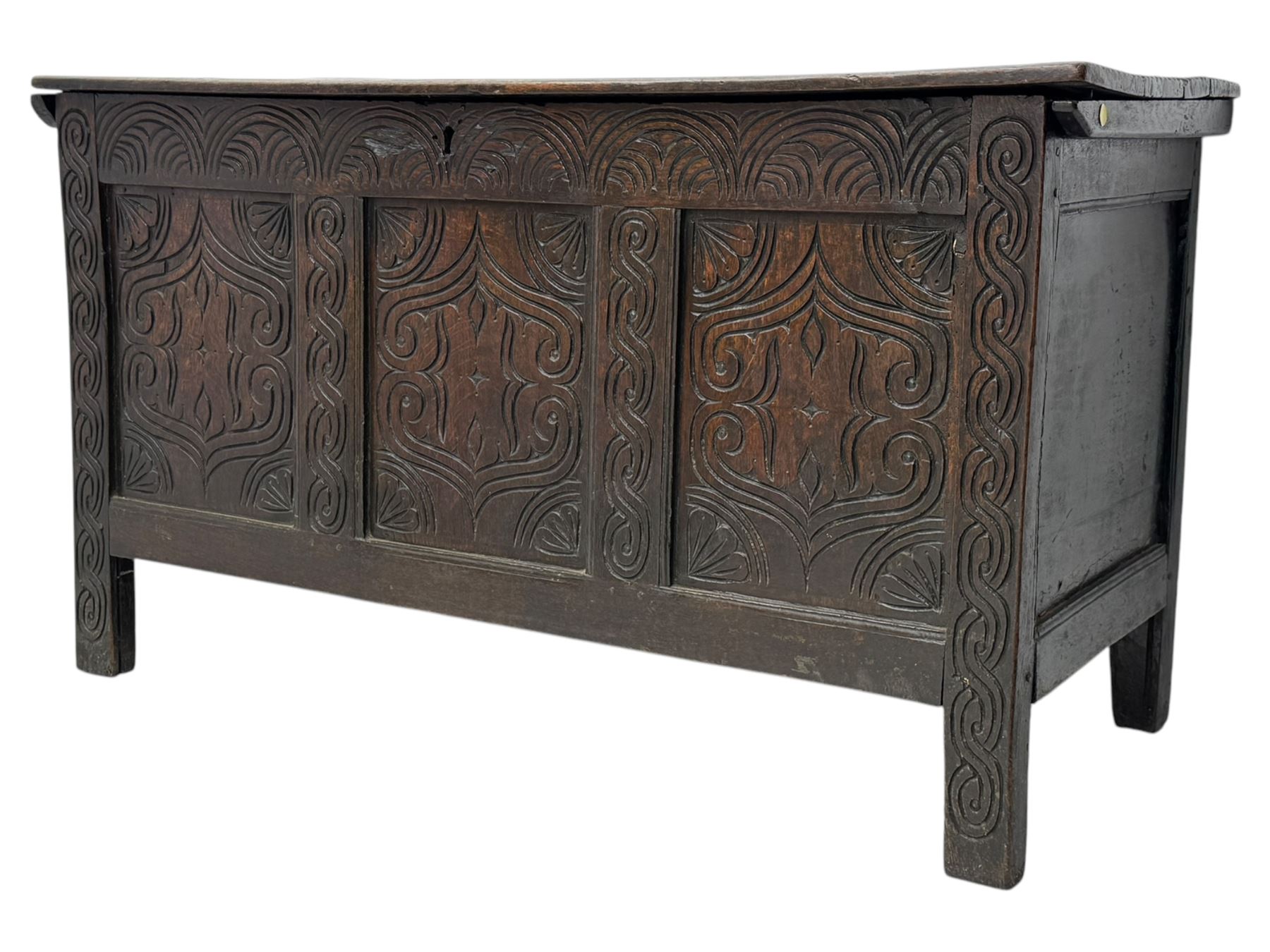 English carved oak coffer, hinged rectangular lid with indented side edges, internal candle-box, front with three-panel front with decorative carvings, raised on stile feet, circa 1700
