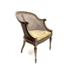 Early 20th century walnut Bergère chair, moulded and shaped frame terminating in rams head, cane woven back meets patterned upholstered seat, raised on leaf carved and fluted supports 