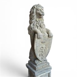 Pair of cast stone Heraldic lions, modelling in upright standing poses with flowing mane, each clasping an Armorial shield moulded with a crowned lion in their forepaws, raised on rectangular pedestals