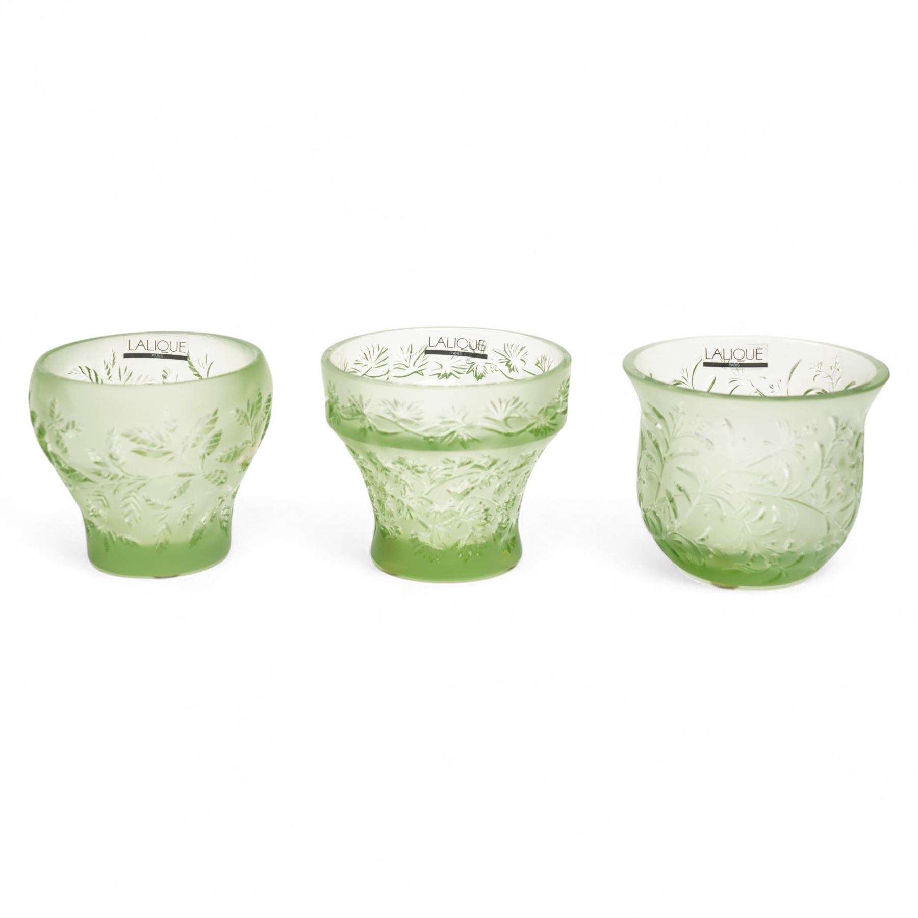 Lalique green glass tea light holder decorated with the coriandre pattern H8cm, another in the basil pattern H8cm and another with trailing leaves H8cm, all signed 'Lalique, France'