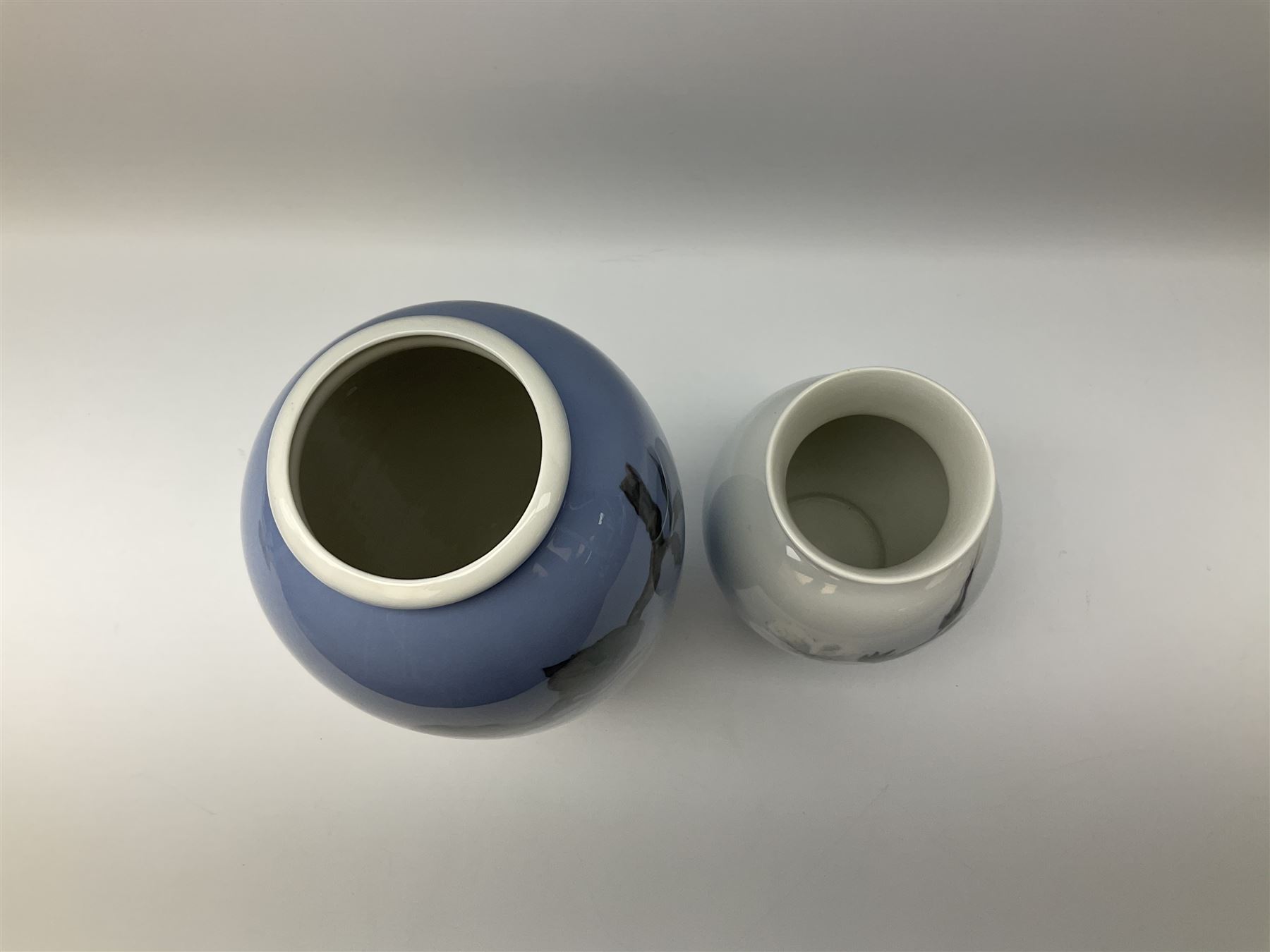 Two Royal Copenhagen vases, first example a vase of baluster form with apple blossom design on a pale blue ground, model no 2629 design no 2129 H27.5cm, second example a vase of ovoid form, with flower and butterfly decoration, model no 2667 design no 36 H17.5cm. 