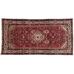 North West Persian Malayer crimson ground carpet, the central ivory lozenge medallion set in a field decorated with Herati motifs, with contrasting geometric spandrels, the multiband border decorated with repeating stylised plant motifs and flower heads