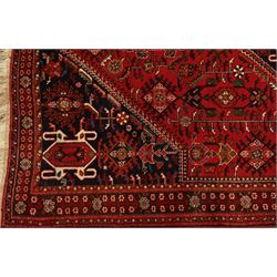 Persian tribal hand-knotted rug, crimson ground, madder field with central stepped lozenge medallion with scattered floral and geometric spandrels with rosette border 