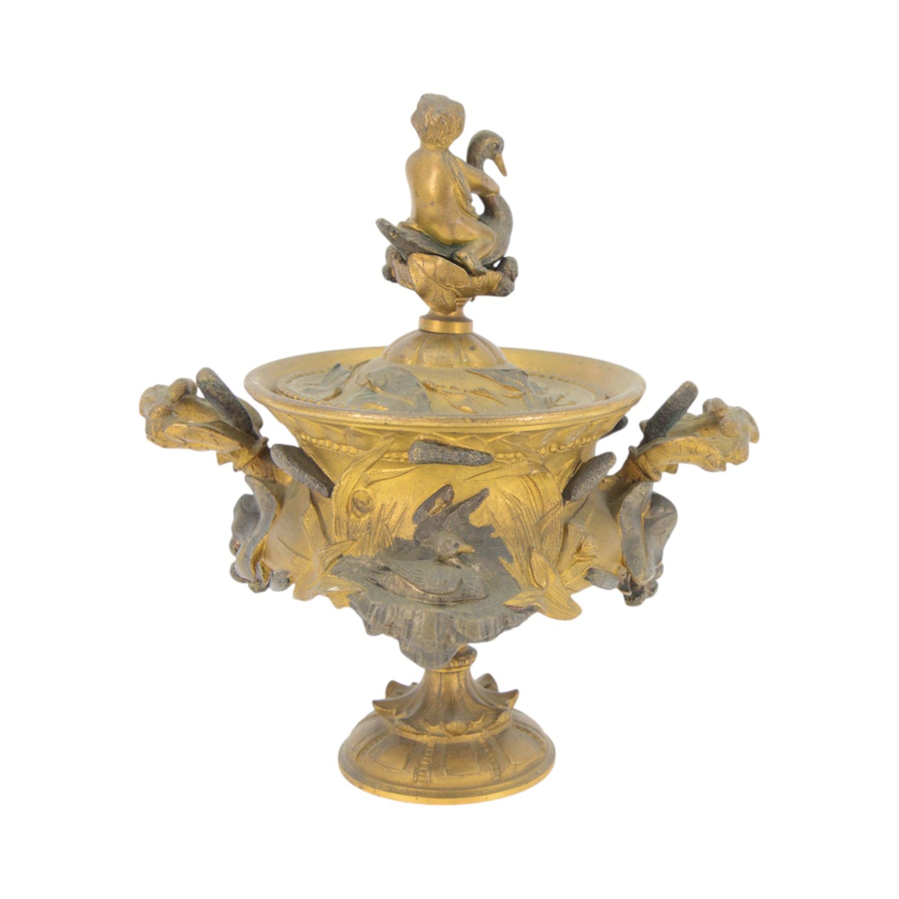 19th century gilt bronze twin handled urn, the removable cover with foliate decoration and finial modelled with a putti and swan, the body decorated in relief with swans and reeds, upon a circular foot, H19cm