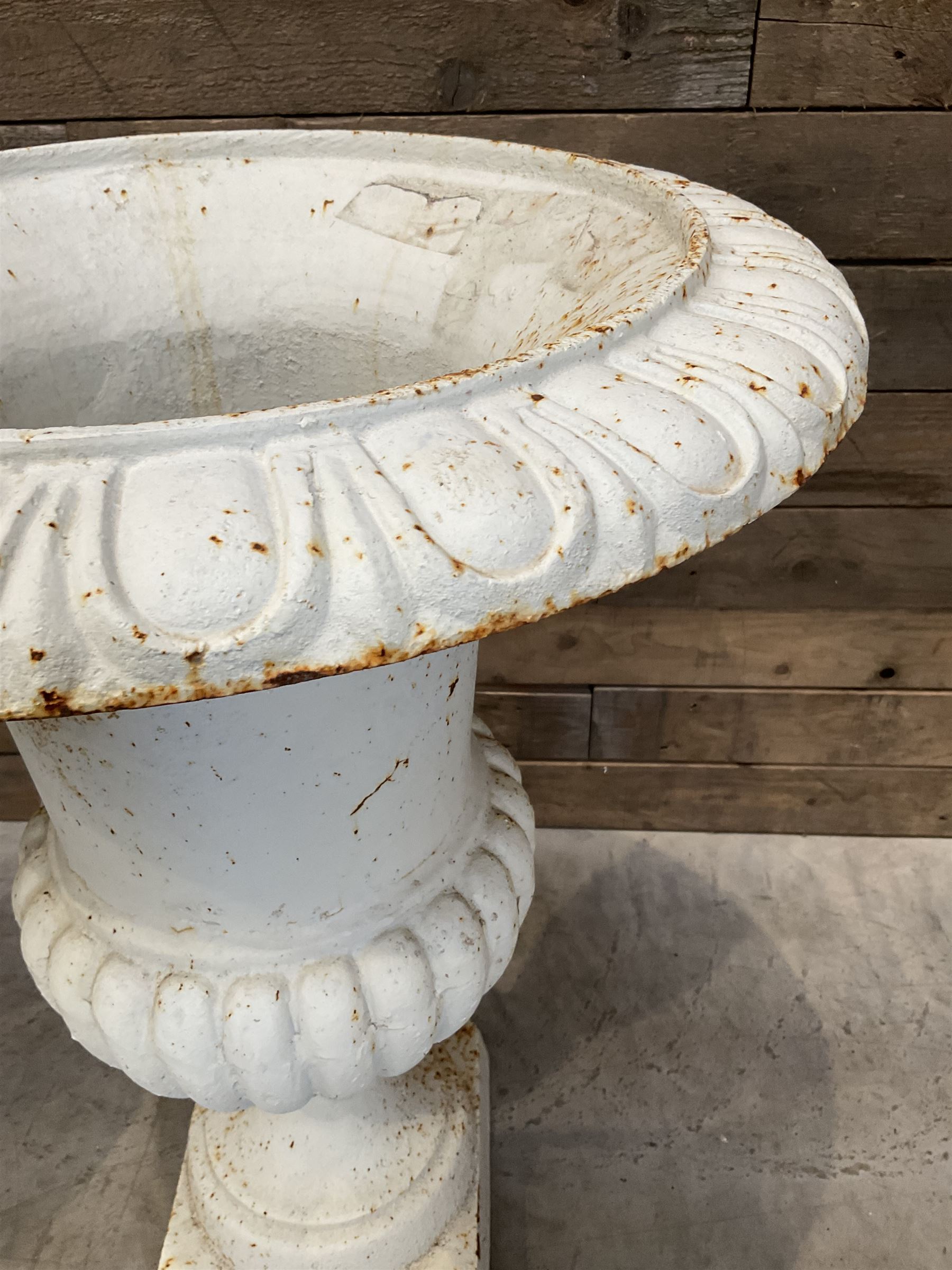 Pair of large Victorian design white painted cast iron campana shaped garden urns, egg and dart rim over a gadrooned underlobe, tapering column on square plinth base