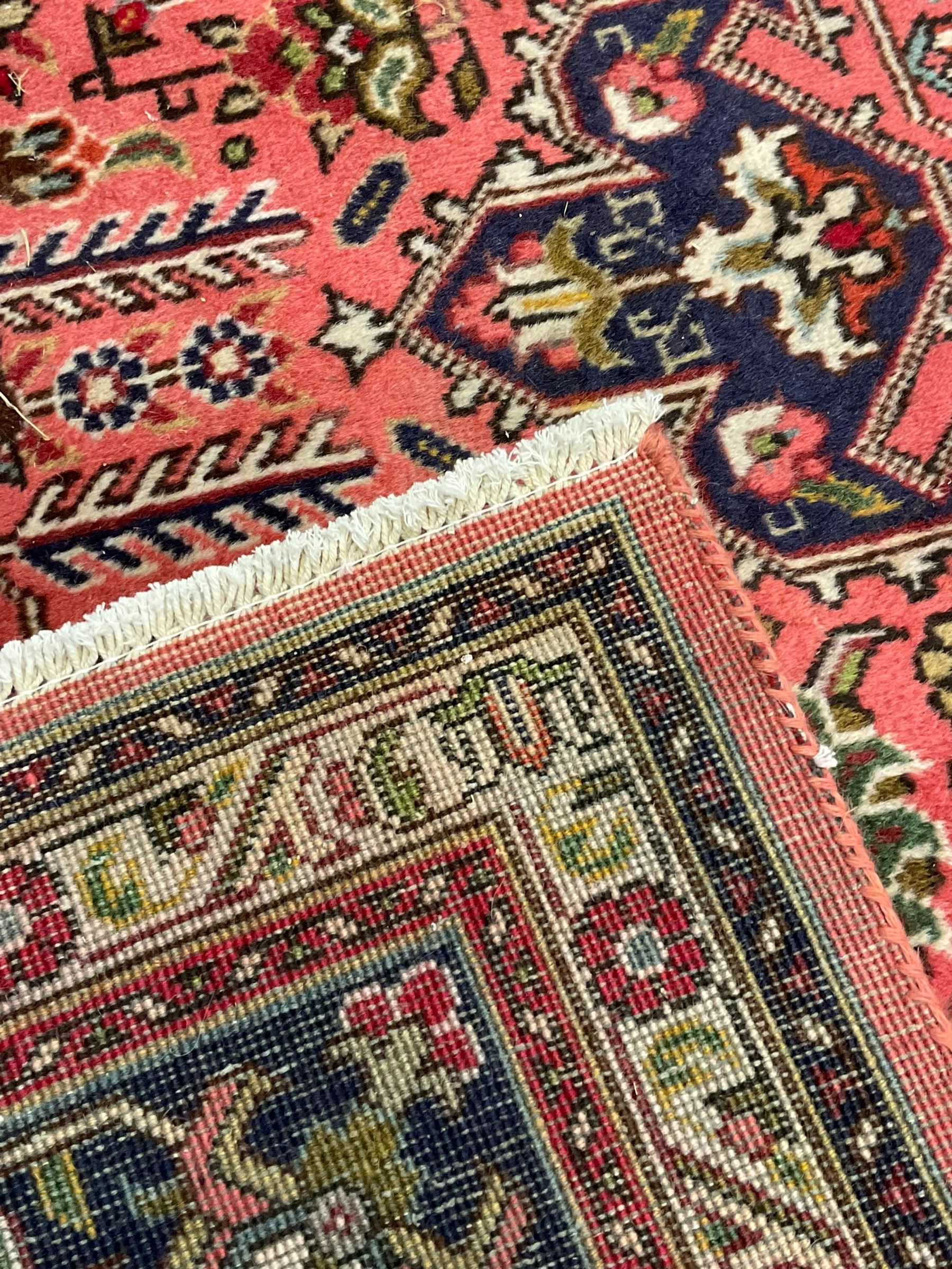 North West Persian pink ground Tabriz carpet, central indigo ground medallion surrounded by stylised plant motifs and trailing foliage, the main border with overall floral design within guard stripes 