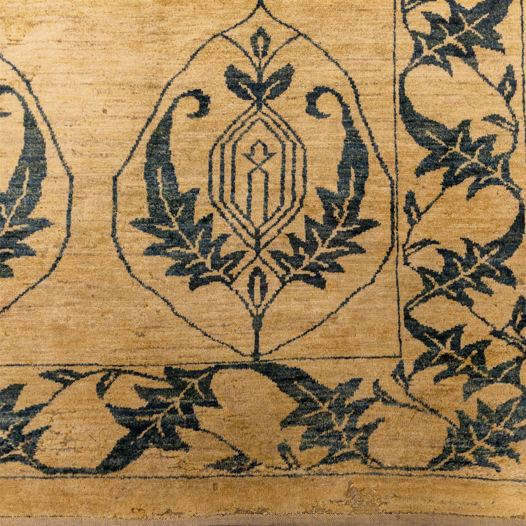 Late 20th century Turkish hand-woven carpet, golden beige field decorated with a repeating lattice of stylized medallions enclosing boteh and angular foliate motifs linked by issuing scrolling vinery within a border of complementary stylized leaf scrolls