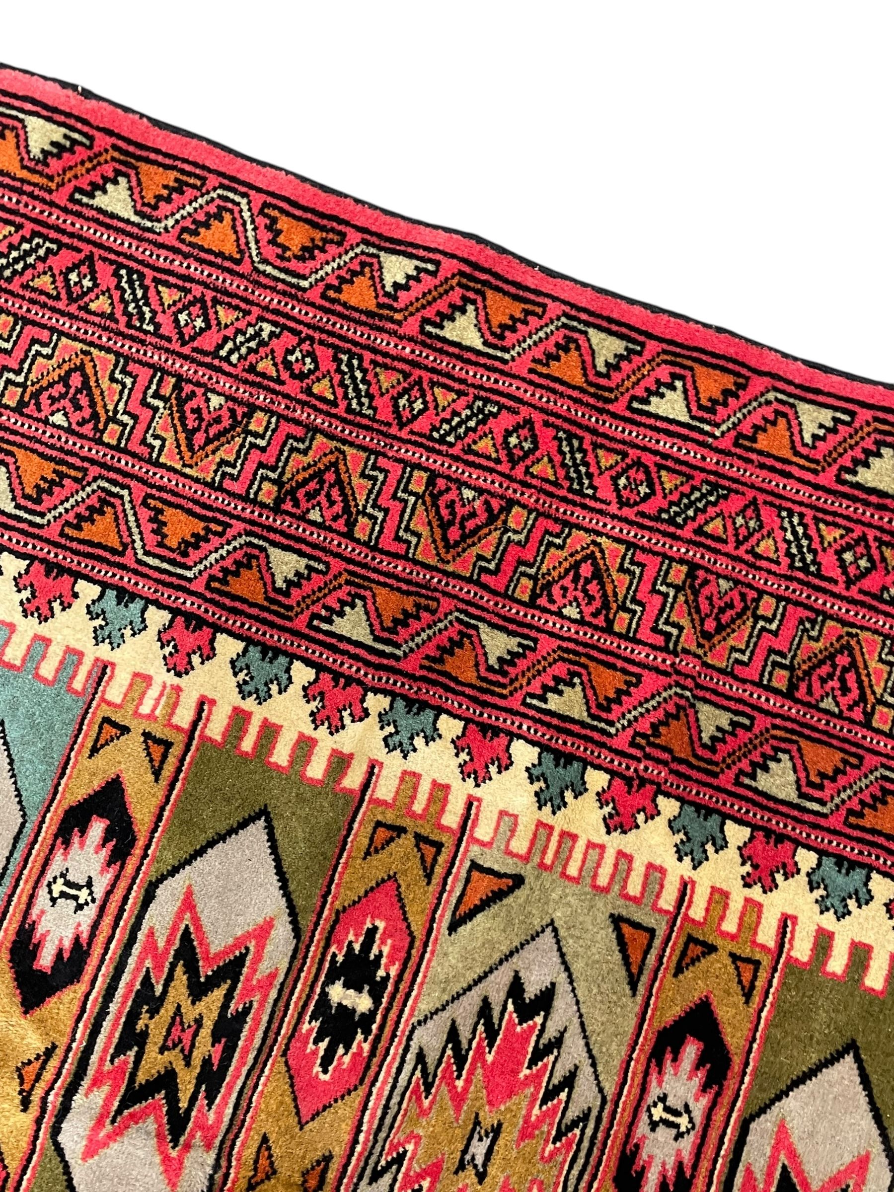 Turkaman red ground rug, the field divided into horizontal rows and decorated with geometric motifs, intricately pattern borders and end panels