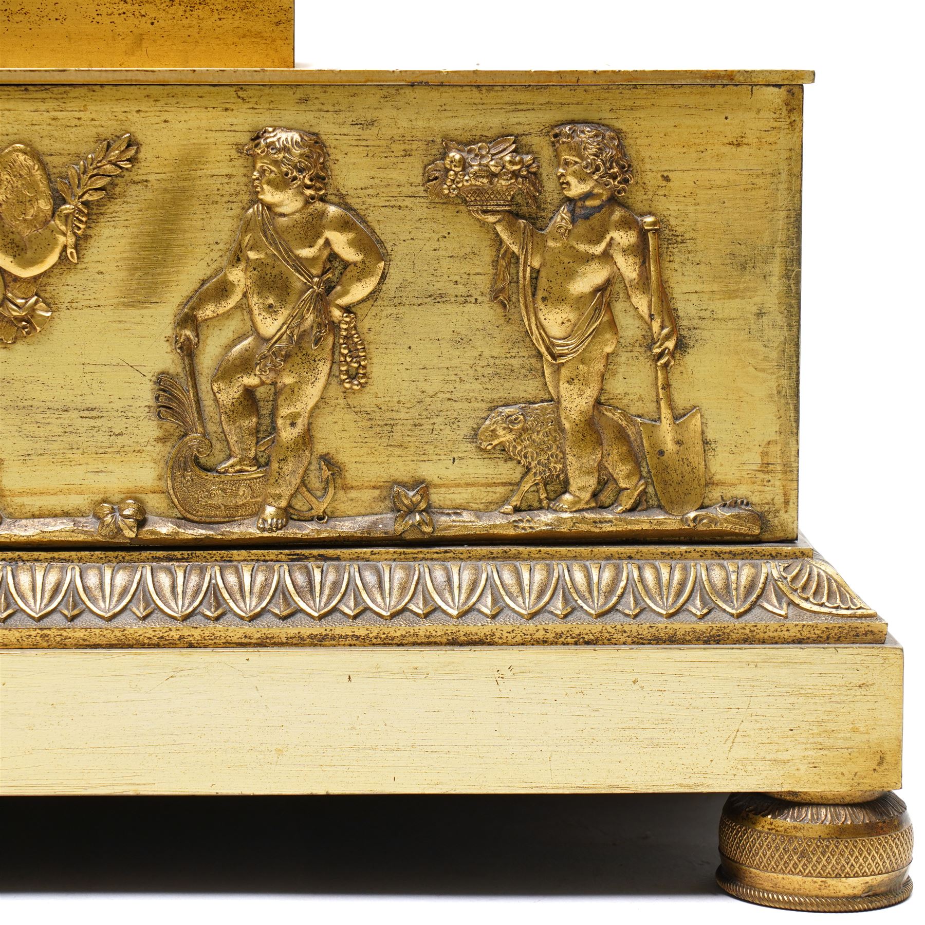 Empire period-gilt brass early 19th century French figural mantel clock c1820, the case surmounted with a figure of Ceres the Roman goddess of plenty holding a cornucopia overflowing with fruit and corn, supported on a rectangular plinth base with depictions of putti representing the arts and labour, movement case with floral garlands and a leaf and ribbon dial bezel, convex white enamel dial with moon hands and short Roman numerals, with a  Parisian 8-day twin-train countwheel striking movement and silk suspension, striking the hours and half-hours on a bell.
With pendulum and key. 