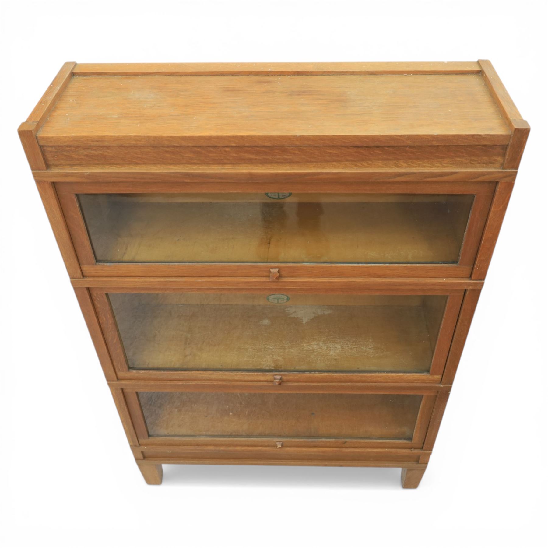 Globe Wernicke - Modular oak sectional bookcase, the three glazed up-and-over doors with panelled sides, raised on a plinth base with square supports