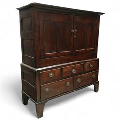 18th century oak dwarf press cupboard, the upper section with twin arched panel doors above three short and two long drawers, each with brass plate handles, shaped apron and stile feet, of compact country form