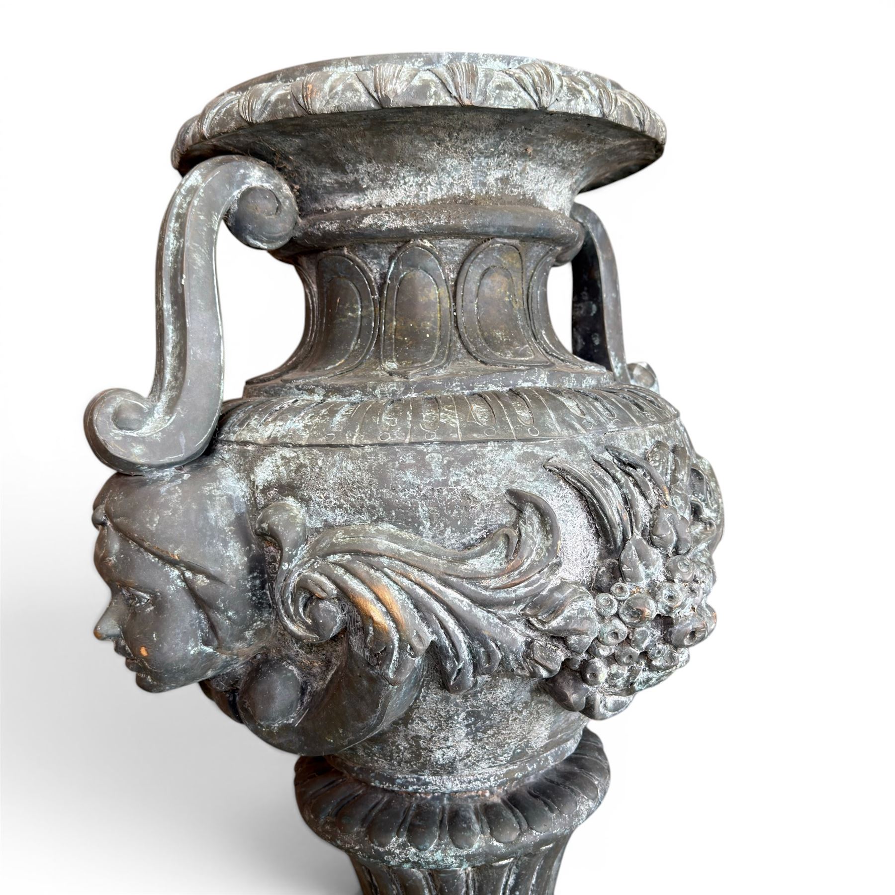 Large impressive Classical cast bronze center-piece urn, twin scroll handles with grape garlands, cherub masks and relief detail, raised on a circular cast stone pedestal with moulded detail