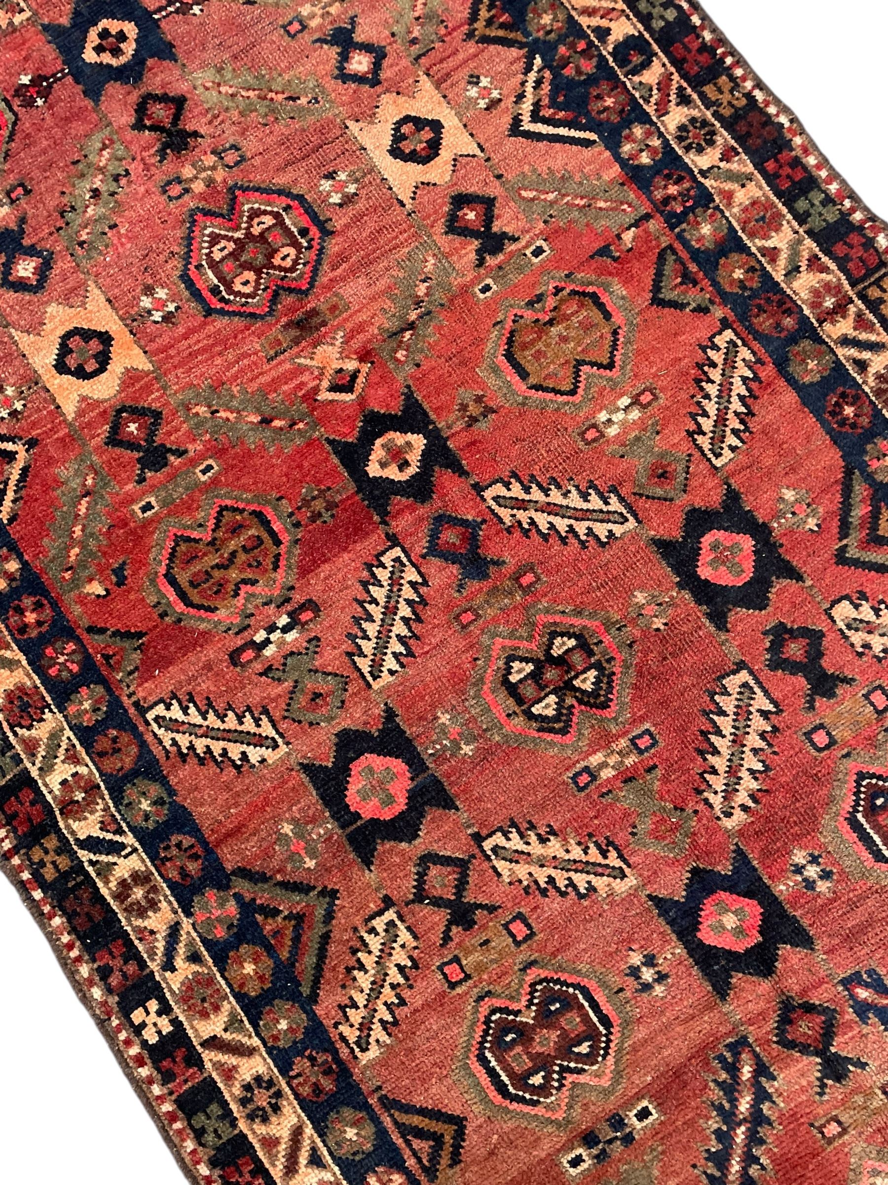 Near pair of Persian Azerbaijan red ground runners, each rug decorated with Nazarlik and stylised leaf motifs, enclosed with three band border decorated with flower heads and geometric motifs 

406cm x 99cm 
409cm x 102cm
