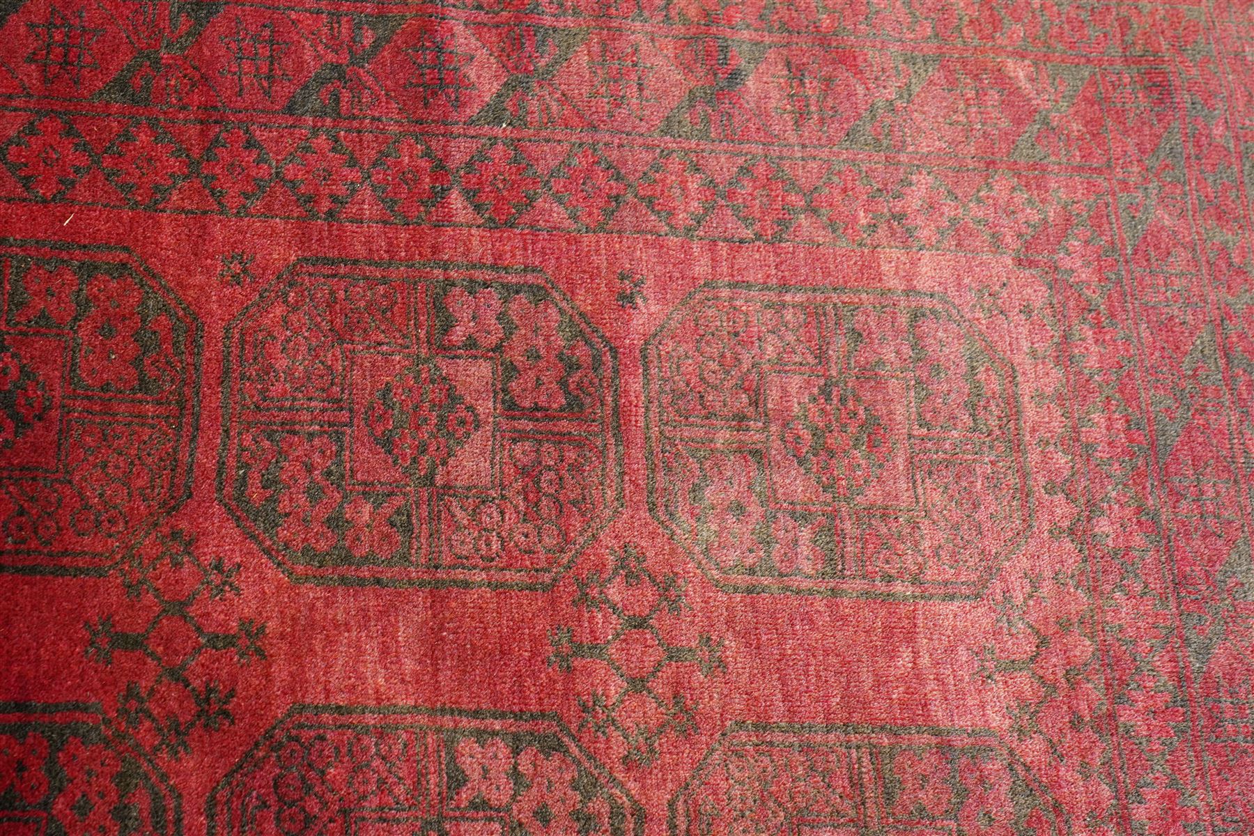 Afghan crimson ground Bokhara rug, the field with three rows of repeating Gul motifs, within six concentric guard bands decorated with repeating geometric patterns