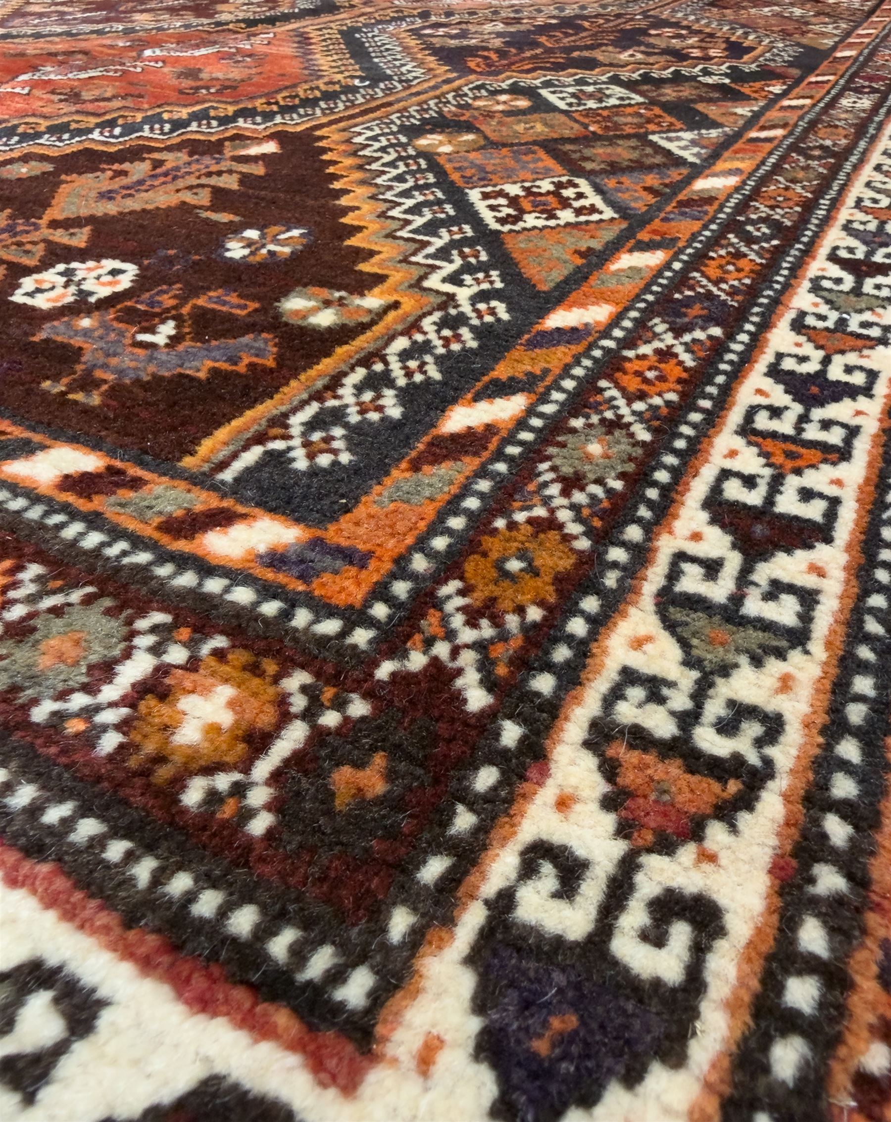 Southwestern Persian Qashqai hand-knotted carpet, the field with a lattice of hexagonal medallions in rust, indigo, and ochre, each containing stylised tree and floral motifs, flanked by lozenge panels with geometric designs, enclosed by multiple borders with rosettes and leaf motifs