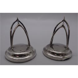 Modern silver mounted bottle coaster, with plain sides and turned mahogany base, hallmarked London 1981, makers mark W.E.V., D12.5cm, together with a pair of silver place card holders in the form of wish bones, hallmarked The Usher Manufacturing Co, Birmingham 1912, (3)