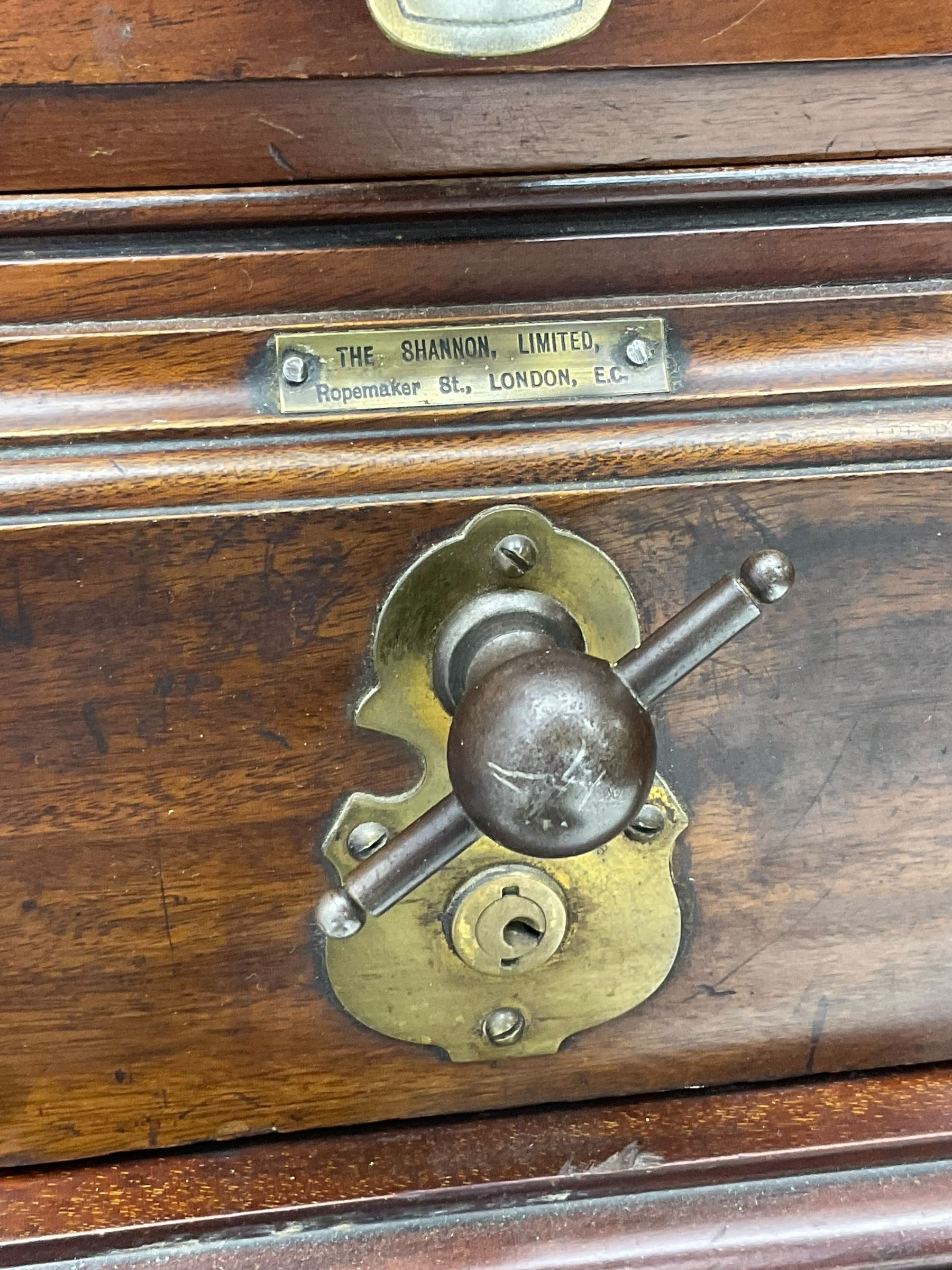 The Shannon Limited - late Victorian walnut filing cabinet, fitted with twenty-four small filing drawers, each with brass handle with label holder, fluted uprights, double cupboard below enclosed by two panelled doors, on turned feet, with brass plaque inscribed 'The Shannon, Limited, Ropemaker St. London, E.C.'