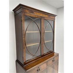 Late 20th century mahogany bookcase on cupboard, the projecting cornice over two doors with curved astragal glazing, two drawers and double cupboard below, the cupboard enclosed by two doors with oval figured veneers, shaped apron and out splayed bracket feet