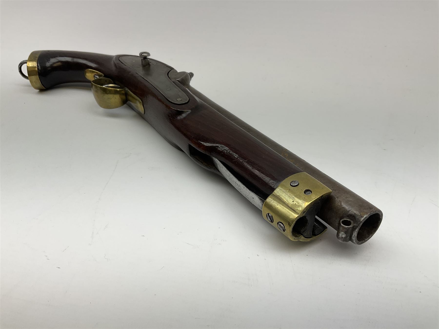 Early 19th century percussion cap cavalry pistol with round 23cm unsighted barrel, borderline engraved action lock (lacking hammer), walnut full stock with heavy brass furniture, iron lanyard ring to the flat butt cap and long flat retaining spring below fore-end for captive ramrod (missing) L41cm overall