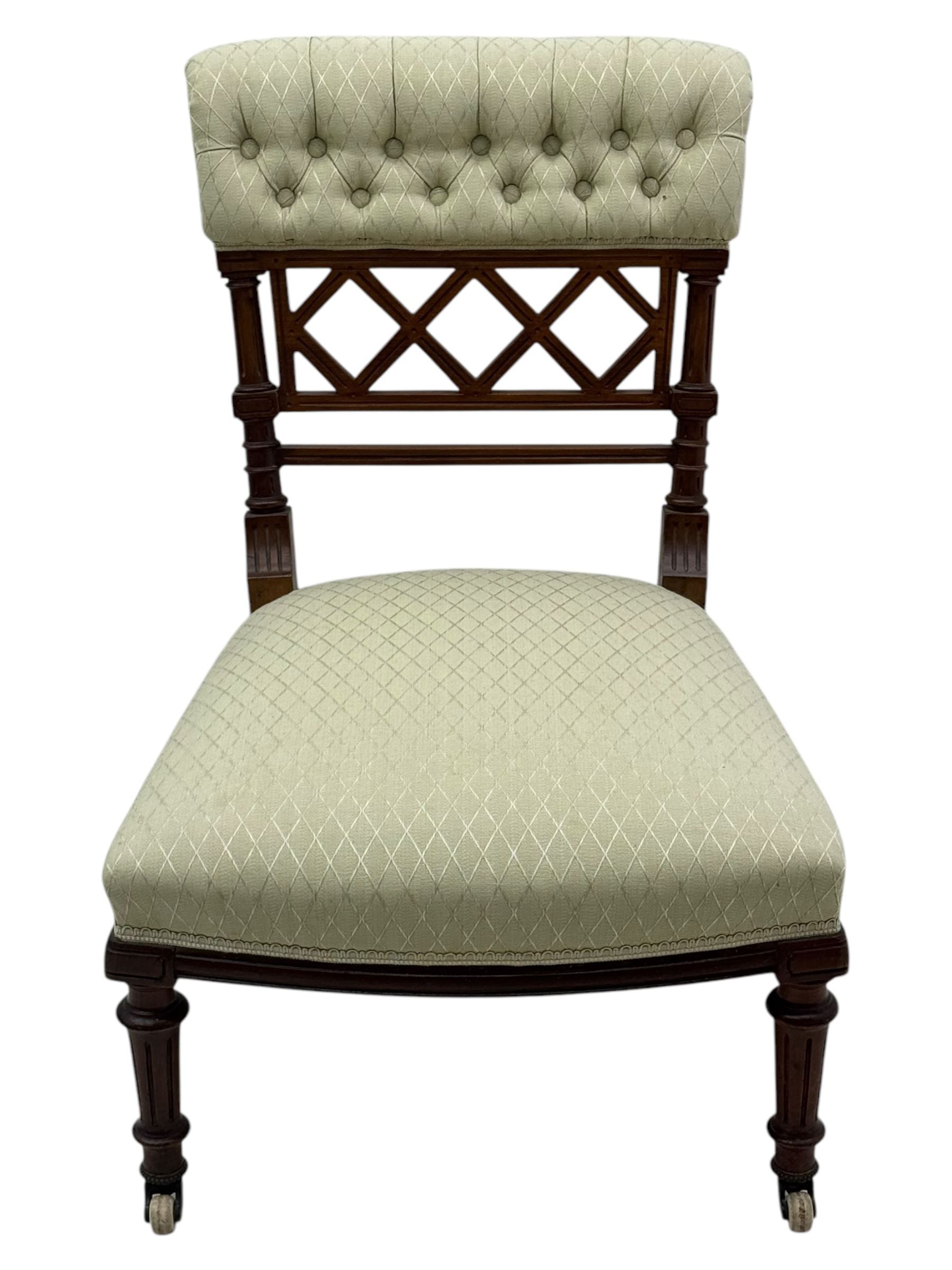 Late Victorian upholstered armchair, with high camel back and deep seat, padded arms and backrest in crimson and cream damask-style fabric, raised on turned ebonised front supports with ceramic castors (H88cm, W65cm, D 60m); and an Edwardian bedroom chair with button upholstered rail back (H72cm, D64cm, W53cm) (2)