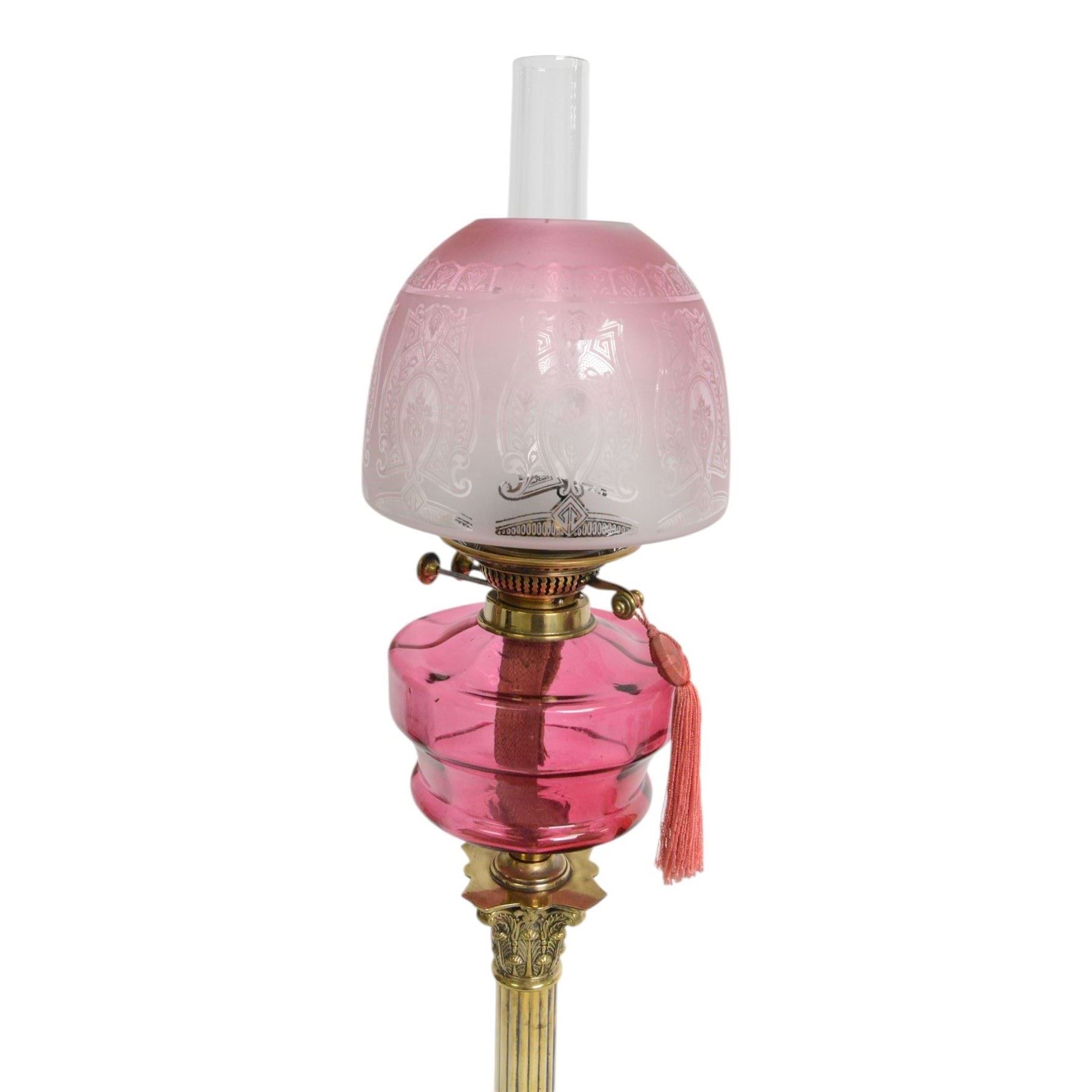 Victorian brass oil lamp, the Corinthian column supporting a cranberry glass burner and opaque etched cranberry glass shade and clear glass chimney, overall H77cm