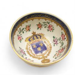 Chinese tea bowl, the enamel decoration depicting floral sprigs within a gilt and blue boarder, with a crowned shield to the centre, together with another bowl and a saucer