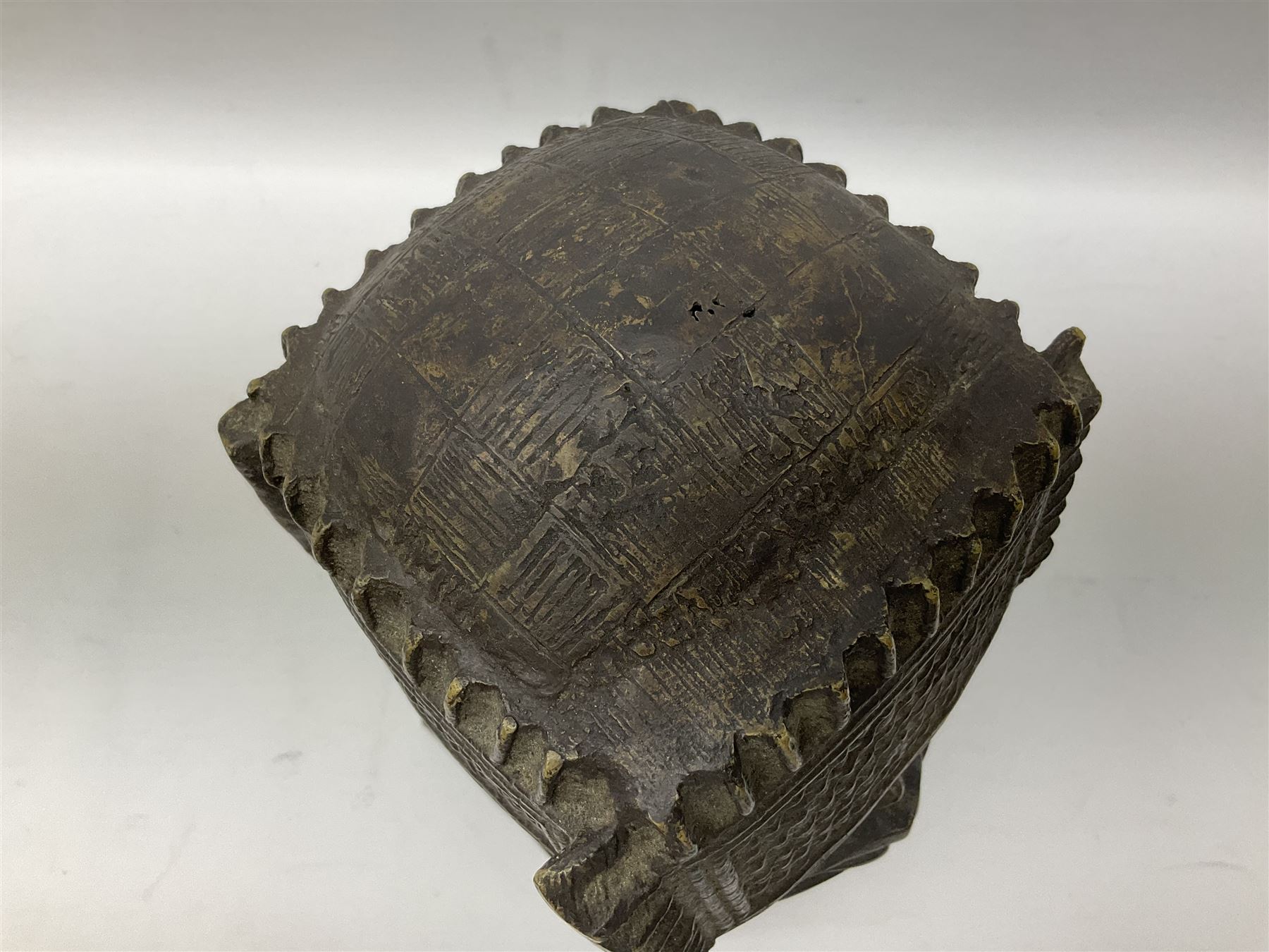 20th century Benin bronze head of an Oba, donning headdress and neck rings with wide open eyes, raised upon a tapering square base, the sides with relief cast knot decoration, H39cm