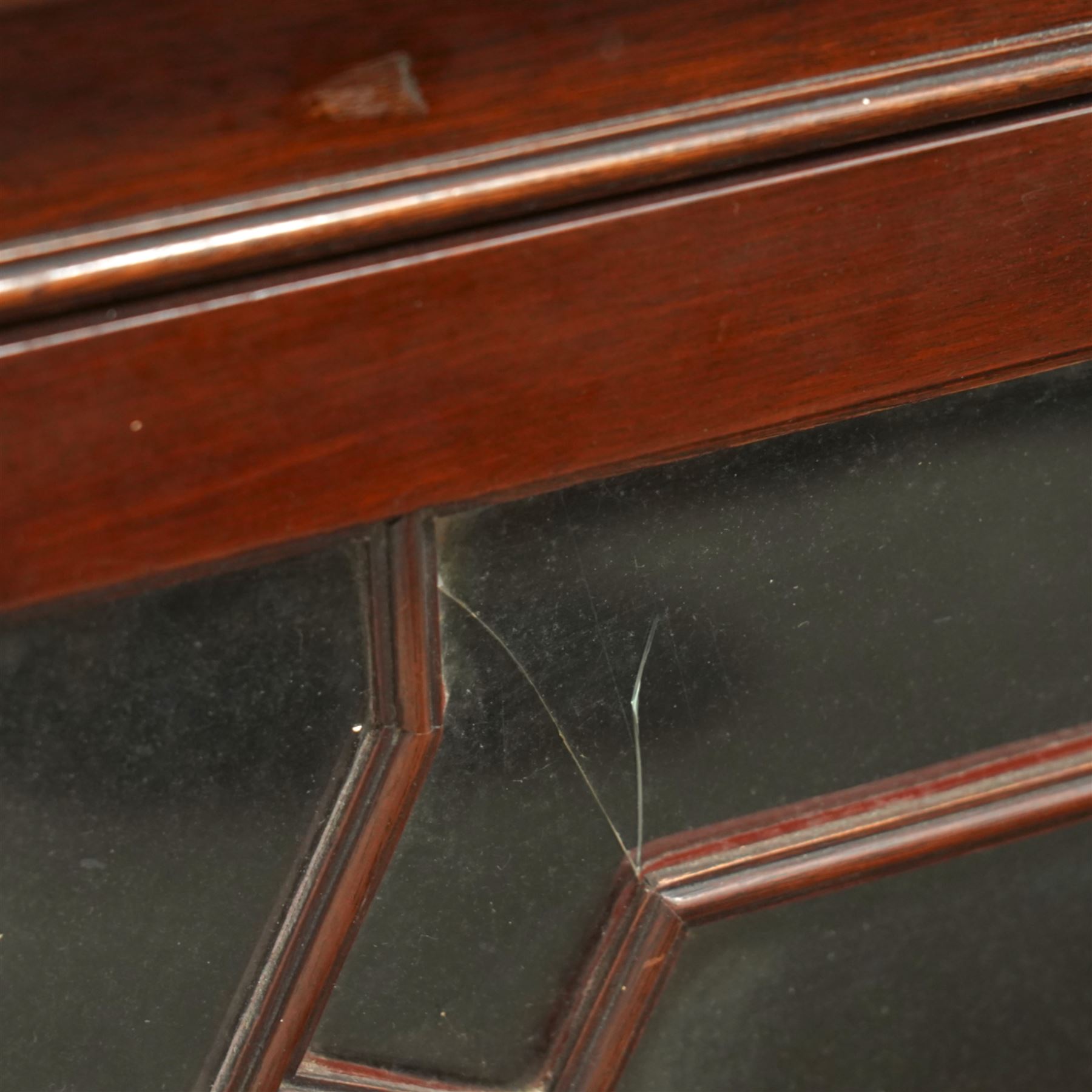 Early 20th century Chippendale design mahogany bookcase, projecting moulded cornice over four astragal glazed doors, the interior fitted with adjustable shelves, on bracket feet 