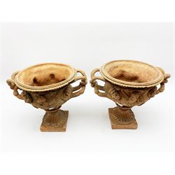 Pair of late 19th/early 20th century terracotta twin handled campagna urns or Warwick vases, decorated in relief with a band of classical male and female masks, above a lower band of lion masks, the handles modelled as twisted vines leading to a fruiting vine beneath a beaded and lobed rim, H29cm