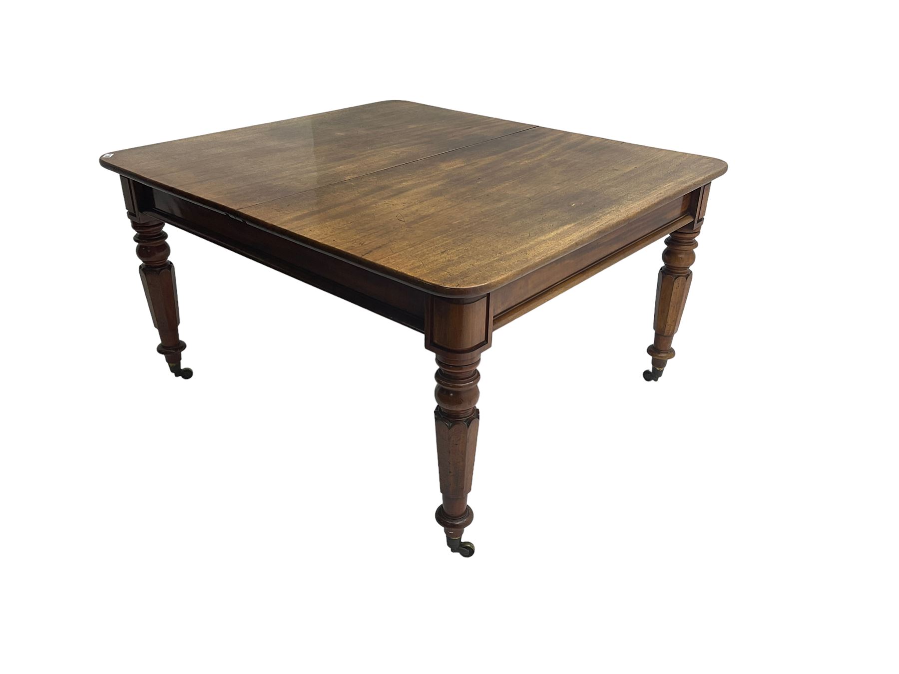 Late 19th century extending mahogany dining table, square top with banded frieze rail, raised on turned octagonal supports with  brass cups and castors, with two additional leaves