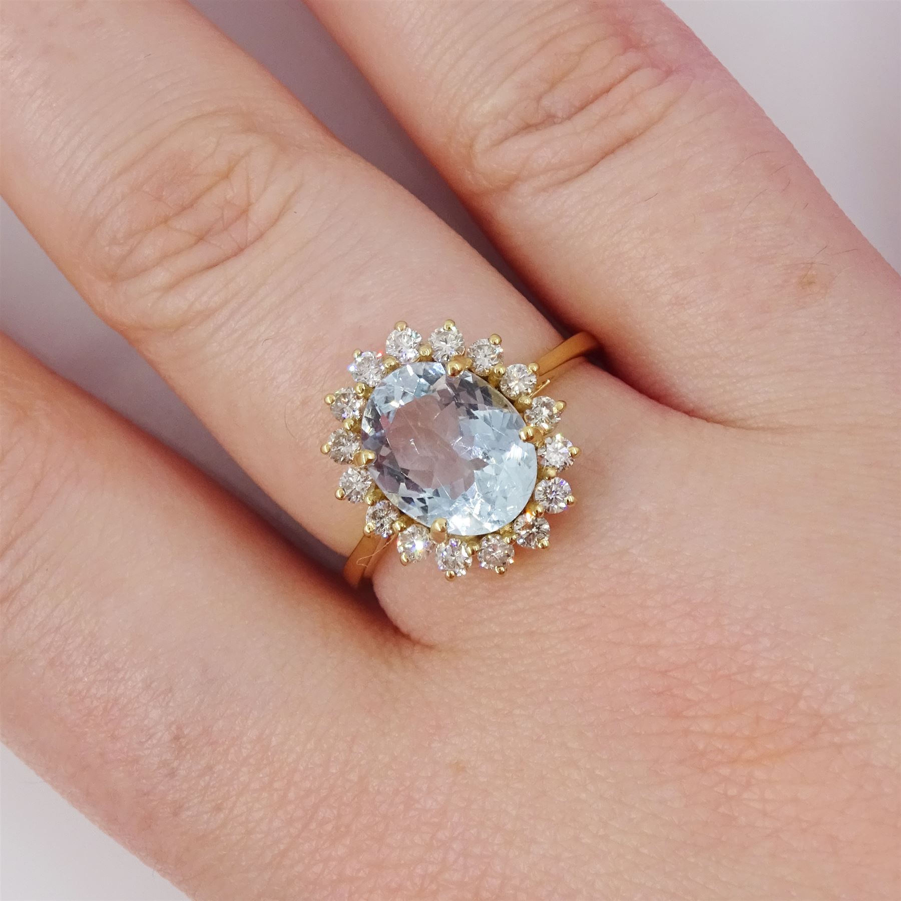 18ct gold aquamarine and diamond cluster ring, single oval cut aquamarine of approx 2.05 carat, surrounded by sixteen round brilliant cut diamonds, stamped, total diamond weight 0.40 carat