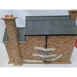 1:24 scale stone effect three-storey cottage dolls house, with green arched door and lattice effect windows, decorated to the interior with wooden floors, wired lighting and fire places, H45cm, W57cm, D26cm