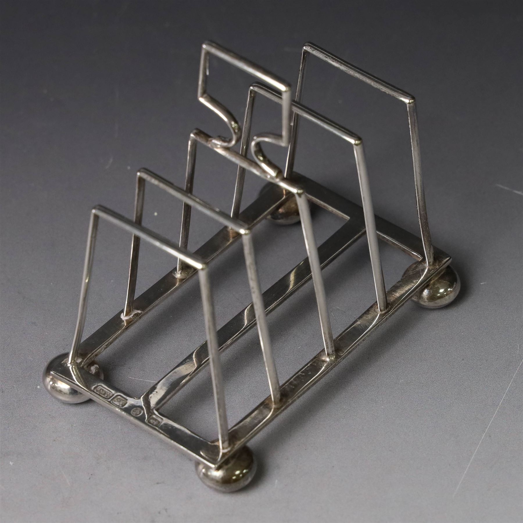 Victorian silver toast rack, with five angular bars and loop handle, upon four squat bun feet, hallmarked Thomas Hayes, Birmingham 1893, height including handle H10cm