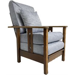 Arts & Craft oak reclining armchair with folding footstool, the upright splats pierced with stylised tulip decoration