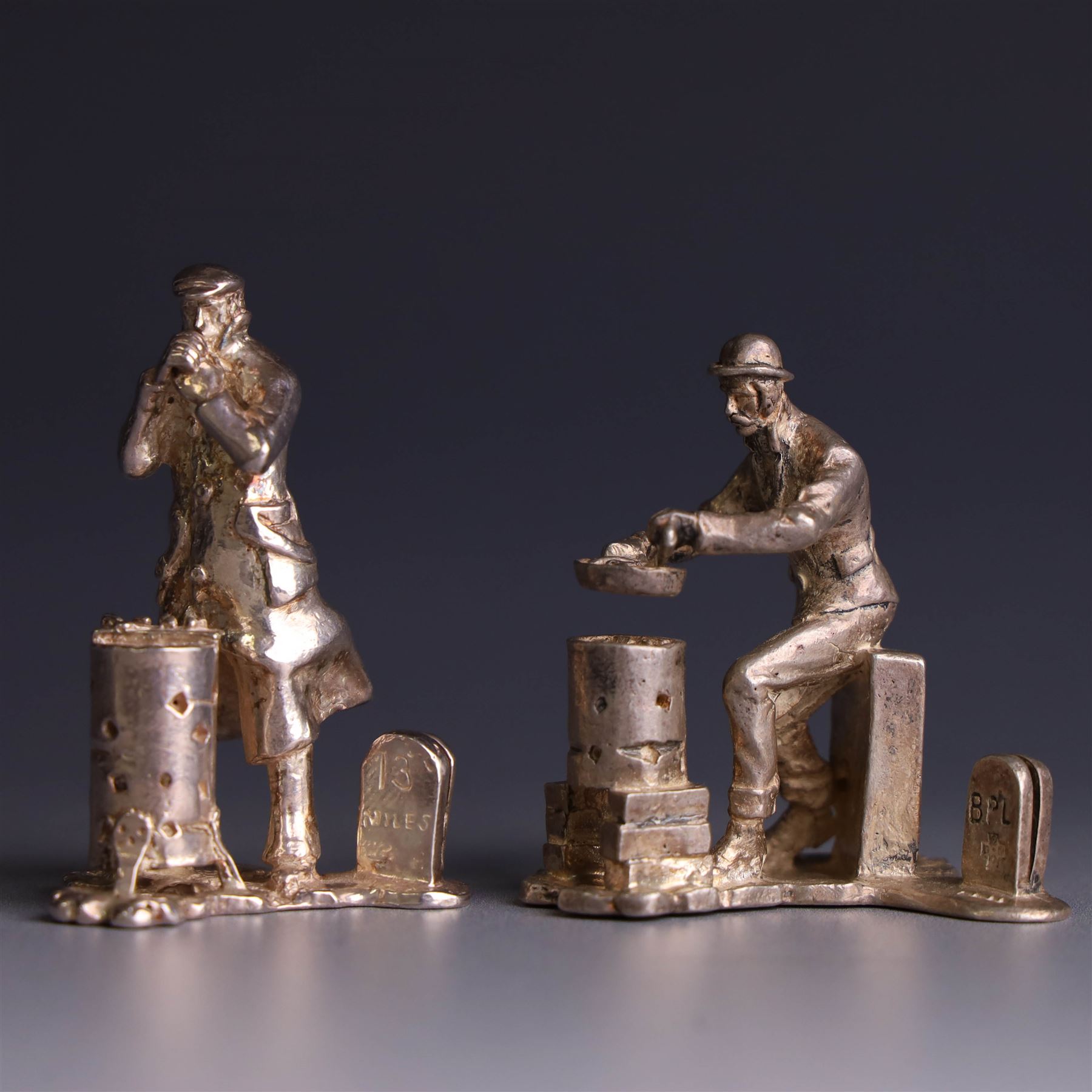 Two silver place card holders from the 'Cries of London' series, each depicting traditional London street traders, hallmarked Thomas Charles Jarvis, London 2000, tallest H5cm